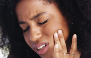 Toothache, sad and face of African woman at home for dental decay, poor oral hygiene and gum health pain. Gingivitis, bad breath and cavity bacteria with person for inflammation, tmj and crisis